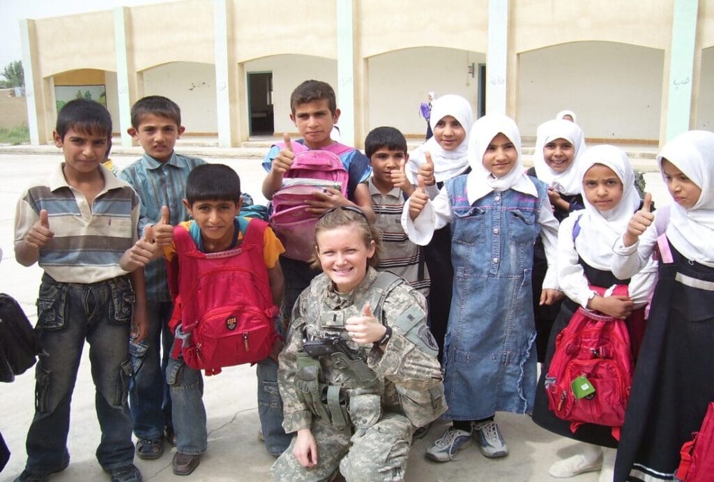foto de jennifer o., enlace militar de la escuela primaria TOPS, con uniforme militar, junto a un grupo de niños